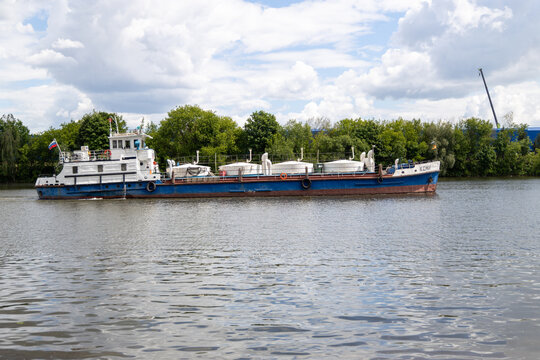Russia. Moscow. May 31, 2026 Kolomenskoye Park. Industrial cargo ship boat named Komi floating on water river surface against green trees bank