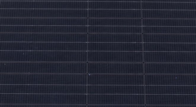 Closeup of a modern solar panel surface, showing the intricate grid pattern of photovoltaic cells and thin conductive busbars used for renewable energy generation and sustainable power technology