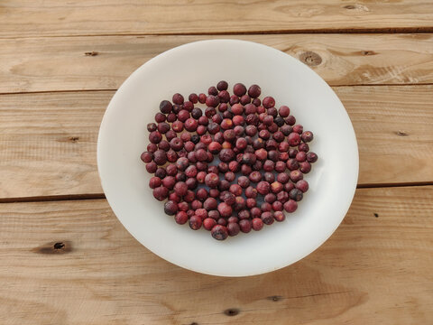 Fresh phalsa berries on white plate with wooden table