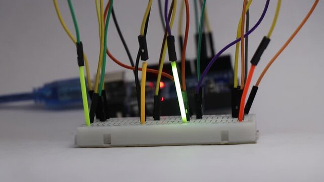 Filament bulb tubes blinking in sequence on a prototype breadboard controlled by a programmable microcontroller on the background