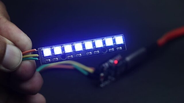 Programmable RGB LED strip with 8 individually addressable LEDs glowing with different colors controlled by microcontroller on the background