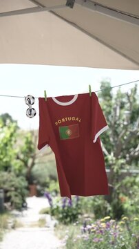 Portugal football supporter shirt with soccer sunglasses on clothesline, natural garden background blurred
