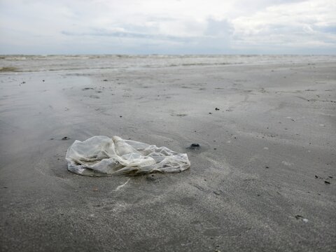 Discarded plastic bag on a sandy beach, marine pollution concept.