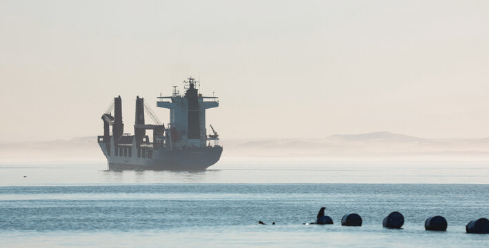 Walvis Bay, Namibia - May 26, 2025: Shipping vessel navigating calm waters of Walvis Bay Namibia during early morning fog