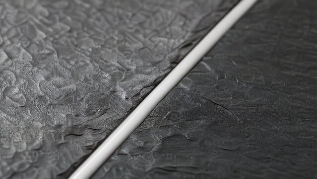 A smooth line of white silicone caulk sealing the seam between two slate tiles.