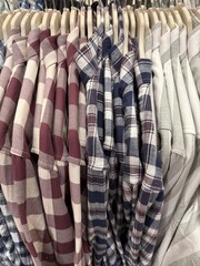 Stack of plaid shirts on hangers in retail store showcasing variety of colors and patterns © dvoevnore