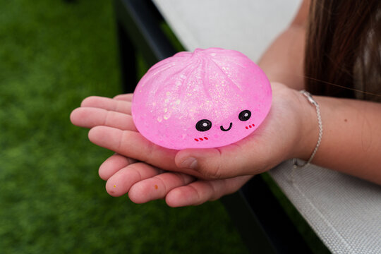 Child&rsquo;s hands holding a pink glitter dumpling squishy, a trendy anti-stress toy for sensory play, relaxation, and focus
