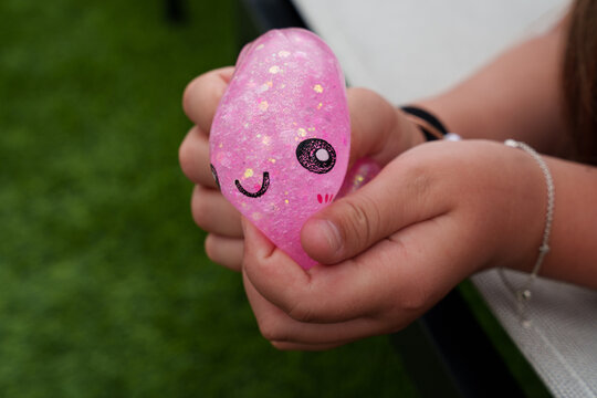 Child&rsquo;s hand squeezing a pink glitter squishy dumpling toy. Sensory play, stress relief, tactile stimulation, fine motor skills development, colorful close-up
