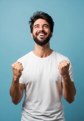 Fototapeta premium Excited Young Man Celebrating Success with Clenched Fists and Joyful Expression on Blue Background