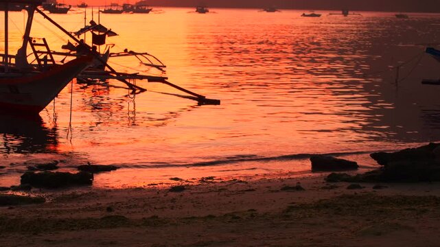 Motorized tricycles pass along a beach road beside glowing sunset water