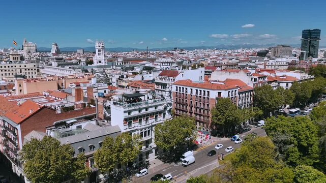 High drone view over central Madrid rooftops and avenue under clear spring sky