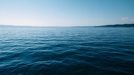 Fototapeta premium A serene view of the blue sea meeting a clear sky under bright midday sunlight