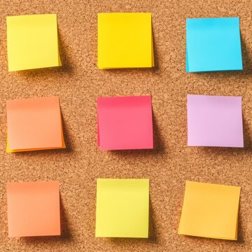 Nine vibrant blank sticky notes in a 3x3 grid on a corkboard, ready for ideas, planning and colorful reminders. Productivity, Brainstorming