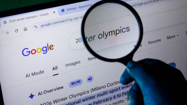 Closeup of a hand holding a magnifying glass over a computer screen showing a google search for the 2026 winter olympics