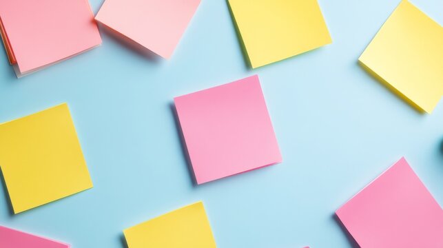 Top view of scattered pink and yellow sticky notes on a light blue background, symbolizing ideas, reminders and creative planning. ,productivity ,stationery