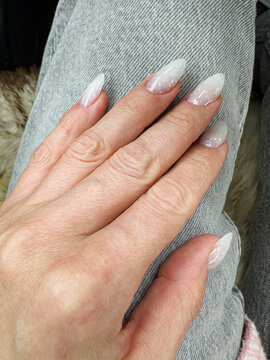 Elegantly Styled Long Nails with a Glittering Ombre Effect on Denim-Clad Hand, Showcasing a Trendy Beauty and Fashion Statement in a Casual Setting