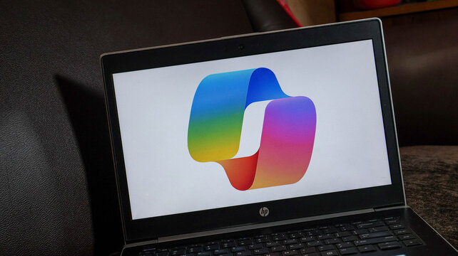 A laptop displaying a colorful logo on its screen sitting on a table indoors