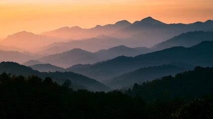 Fototapeta premium Layered mountains are enveloped in a warm golden mist during the dramatic light of sunset or sunrise
