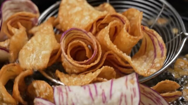Sliced taro root with purple veins deep frying in hot oil and scooped with a strainer