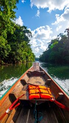 Fototapeta premium Wooden boat navigating river surrounded by lush green trees and blue sky