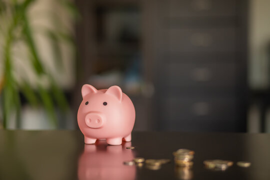 Piggy bank with coins on wooden table at home