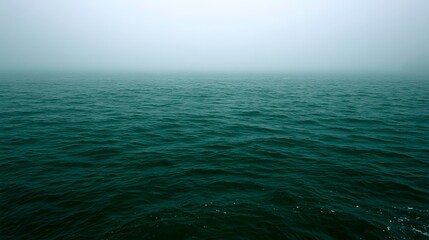 Fototapeta premium An atmospheric view of the emerald green sea shrouded in diffused foggy light creating a tranquil and romantic natural landscape