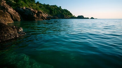 Obraz premium Vibrant emerald sea meets a rocky coastline under the serene light of evening dusk