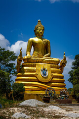 Obraz premium Golden Buddha statue sitting against bright blue sky at the Big Buddha temple in Phuket, Thailand