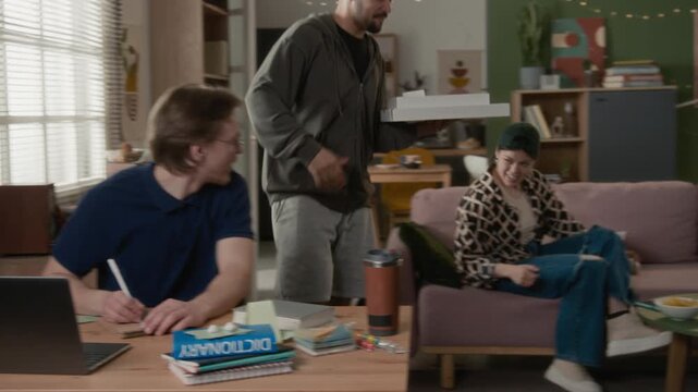 Diverse young adult roommates gathering in living room to open pizza boxes brought by friend, then splitting costs. Food delivery apps, student housing ads, or youth lifestyle marketing campaigns