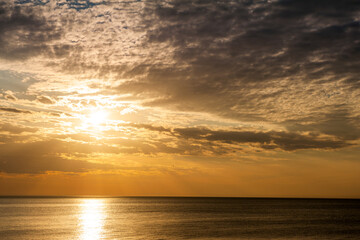 Obraz premium Beautiful sundown background with calm sea and cloudy sky