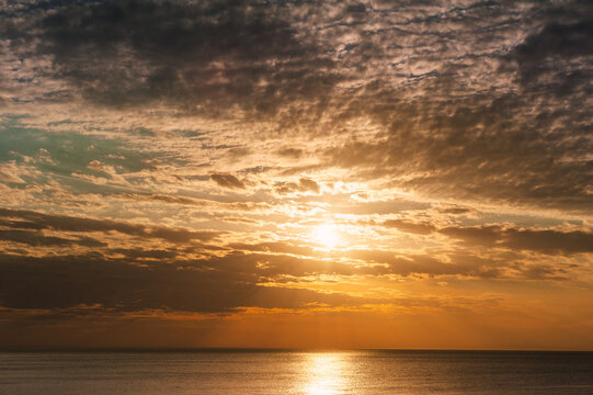Beautiful sundown background with calm sea and cloudy sky