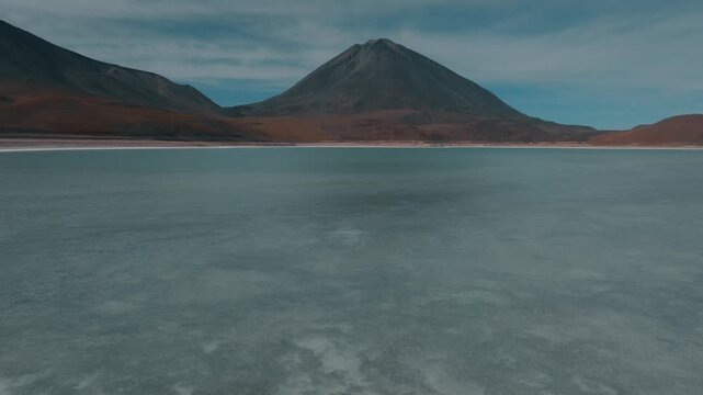 Aerial view of a turquoise Andean lagoon surrounded by volcanic peaks in the remote landscapes of Bolivia&rsquo;s Sud L&iacute;pez region.