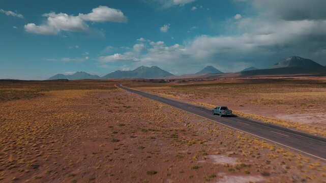 Aerial view of a 4x4 driving across the vast wilderness of Sud L&iacute;pez, Bolivia. Volcanic mountains and high-altitude deserts stretch to the horizon.