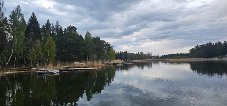 Peaceful lakeside landscapes in Kilsbo, S&ouml;derhamn, G&auml;vleborg, Sweden, with calm reflective water, forested shores, rocky islets, and dramatic cloudy skies. The images capture a quiet Nordic atmosphere