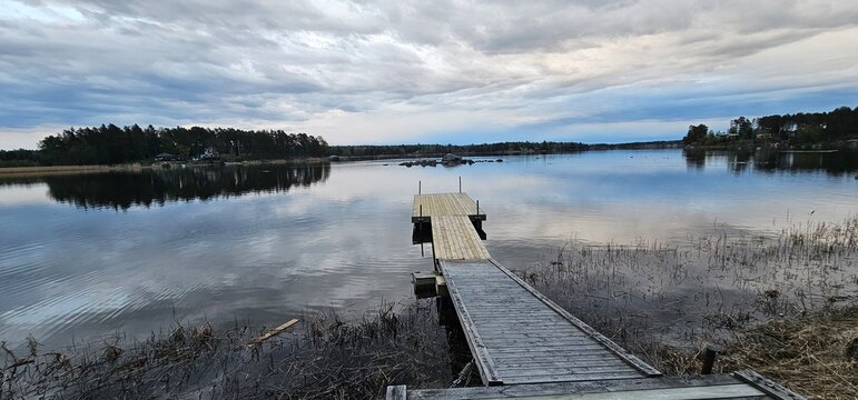 Peaceful lakeside landscapes in Kilsbo, S&ouml;derhamn, G&auml;vleborg, Sweden, with calm reflective water, forested shores, rocky islets, and dramatic cloudy skies. The images capture a quiet Nordic atmosphere