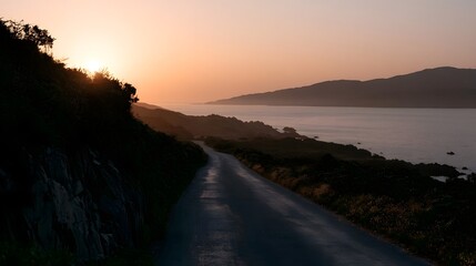 Fototapeta premium A scenic coastal road stretches through the hills under the warm glow of the golden hour