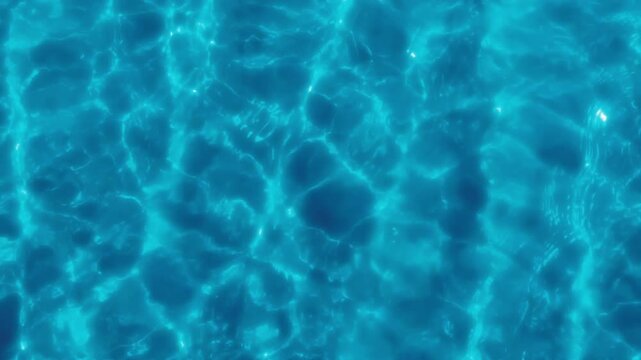 The clear blue water in the swimming pool reflects light. Slow motion