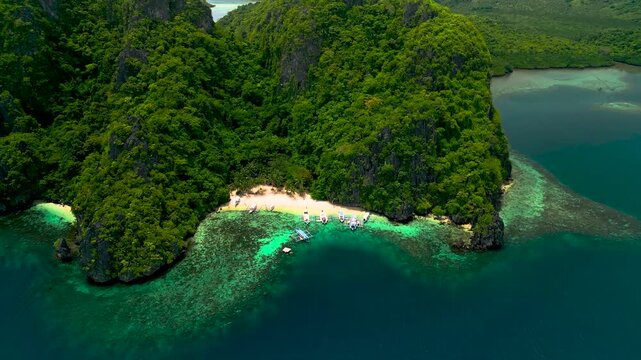 An aerial view of a pristine tropical beach nestled between lush green mountains and deep ocean.