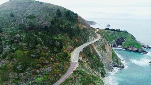 Winding highway follows rugged shoreline through dramatic California scenery