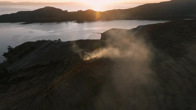 Drone view of a remote island on Lake Titicaca during sunset. Andean landscapes, traditional villages and dramatic shorelines overlook the vast lake.