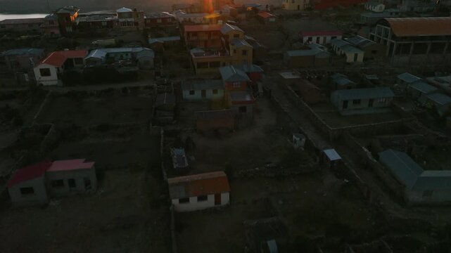 Drone view of a remote island on Lake Titicaca during sunset. Andean landscapes, traditional villages and dramatic shorelines overlook the vast lake.