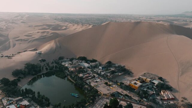 Drone view of Huacachina oasis in Peru, surrounded by towering sand dunes. A unique desert landscape and one of South America&rsquo;s most famous natural attractions.