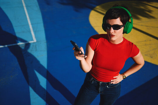 Woman listening to music on smartphone wearing green headphones