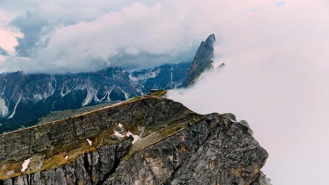 A high altitude view of a rugged rocky mountain peak partially shrouded in thick white clouds