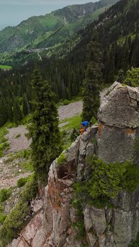 Man athlete climbing on the high rock in the mountains