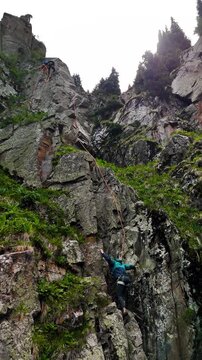 Man athlete climbing on the high rock in the mountains