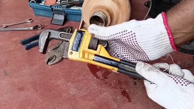 Close Up Of Handyman Adjusting The Knurled Nut To Set The Jaw Opening Size Of A Heavy Duty Pipe Wrench