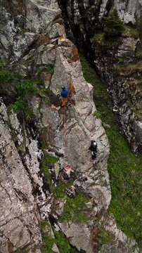 Man athlete climbing on the high rock in the mountains