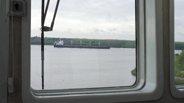 Barco navegando por un r&iacute;o durante un d&iacute;a lluvioso, visto desde el puente de mando de otra embarcaci&oacute;n, transporte fluvial, navegaci&oacute;n, industria mar&iacute;tima y clima adverso