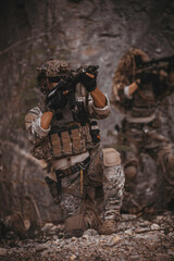 Obraz premium Two armed military operators secure an area during a tactical mission, holding rifles while patrolling a dense forest wilderness for defensive strategy, combat readiness, and national security.